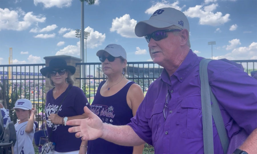 Four fans wearing all purple and white talk to someone just off camera.