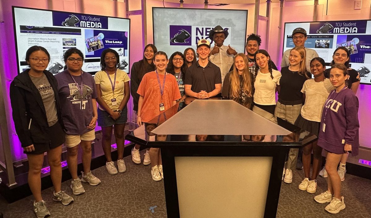 A group of teenage campers pose with in the student media newsroom.